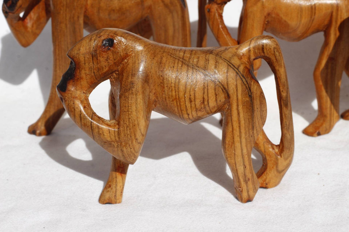 Famille de 4 sculptures en bois d'olivier représentant un babouin/singe marchant/mangeant. Figurines en bois sculpté à la main de couleur marron poli. Cadeaux d'art africain