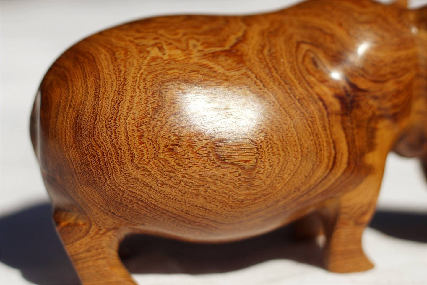 Handgeschnitzte Nilpferdfigur aus Mubanga-Holz. Glatte Safari-Skulpturen aus Sambias Kiaat. Einzigartige Holzmaserung auf einem Stück hellbraunen Hartholzes.