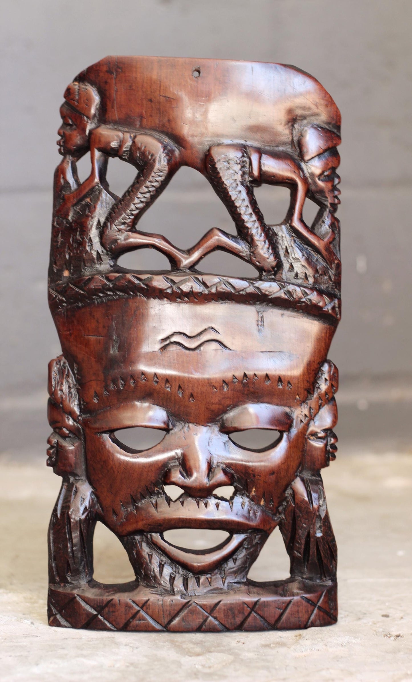 African Man Face Self Standing Mask with villagers performing chores Carvings. Handcarved interior decor tribal art. Brown iron Wood Decor.