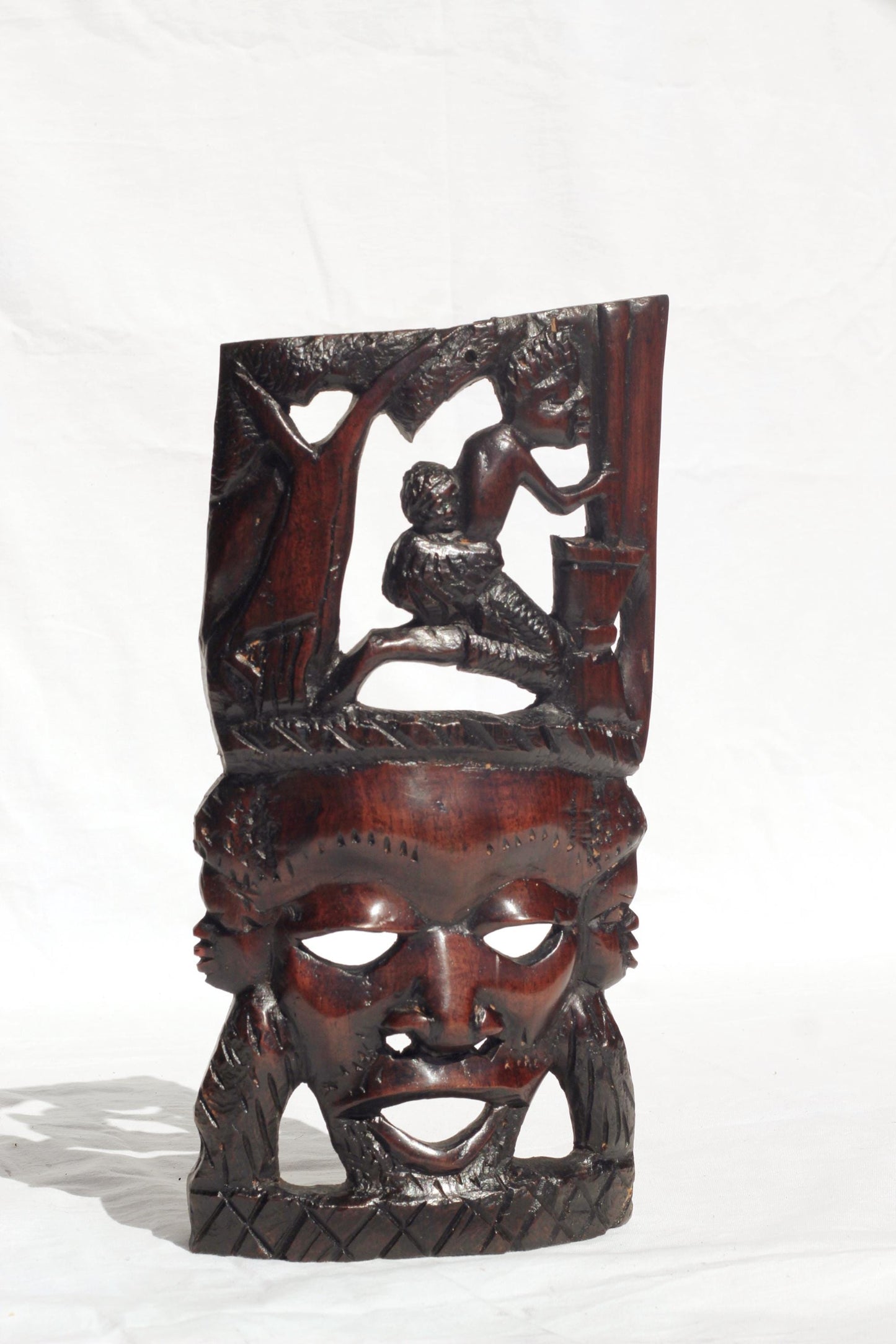 African Man Face Self Standing Mask with villagers performing chores Carvings. Handcarved interior decor tribal art. Brown iron Wood Decor.