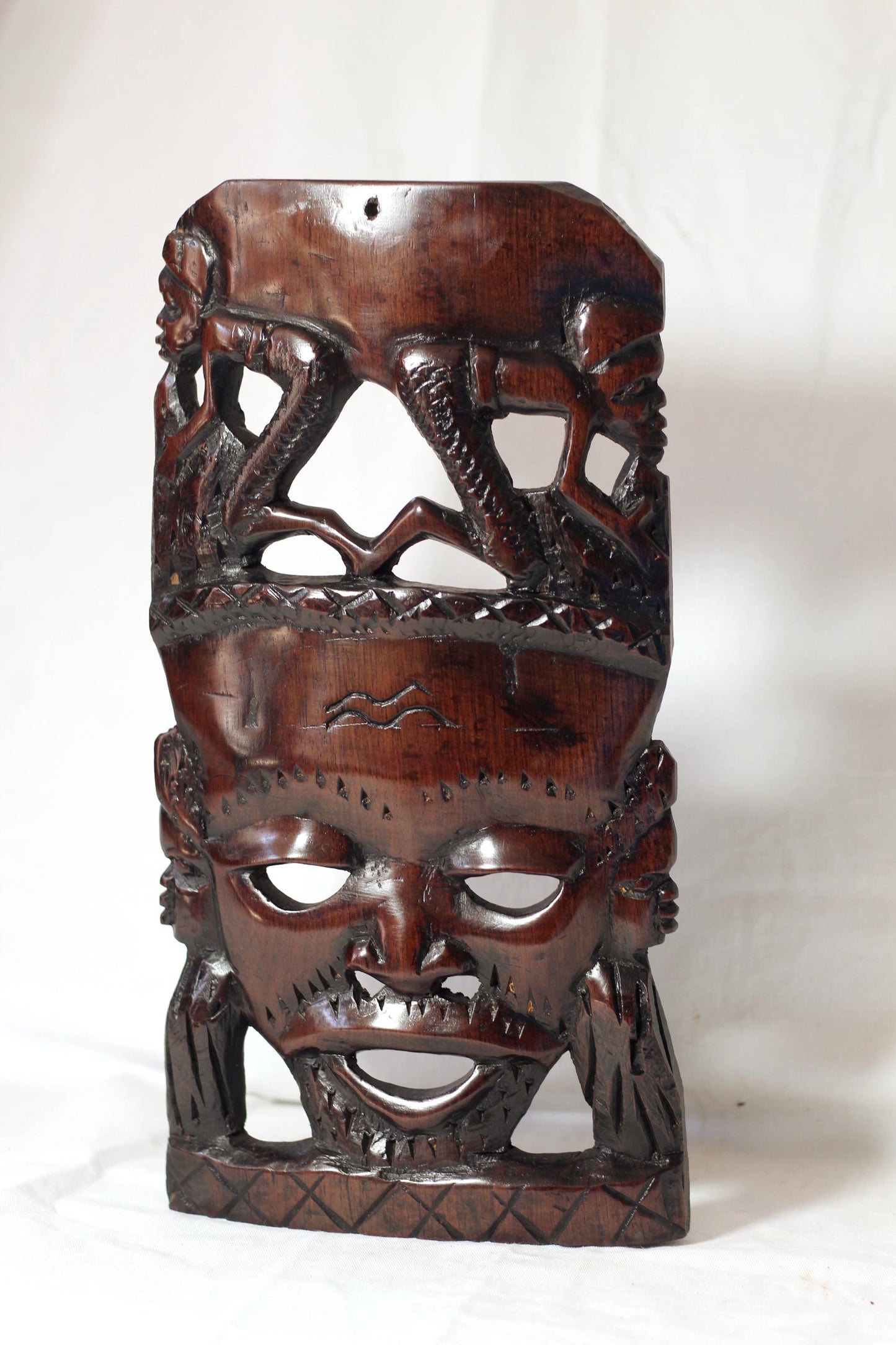 African Man Face Self Standing Mask with villagers performing chores Carvings. Handcarved interior decor tribal art. Brown iron Wood Decor.